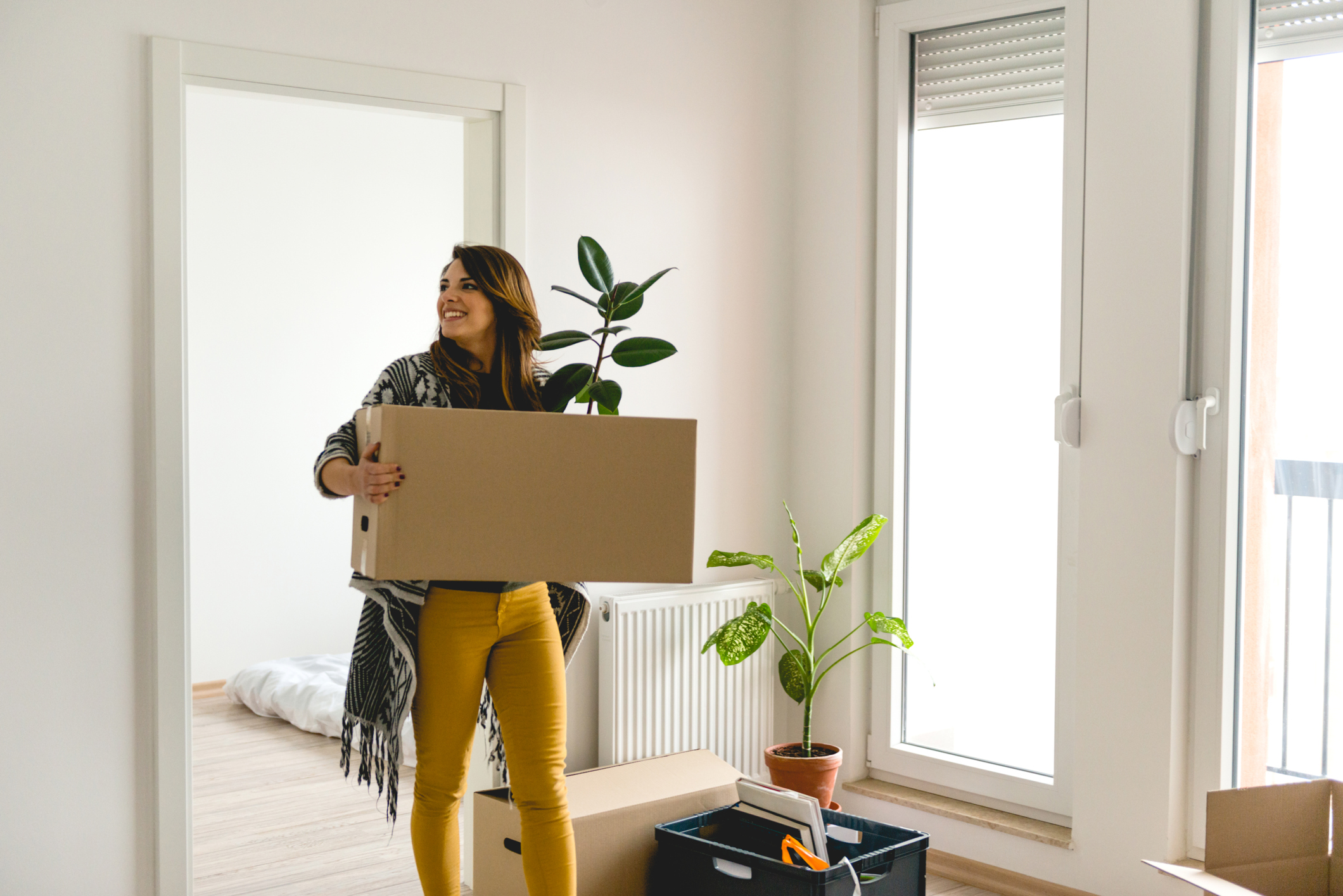 travel-phsyical-therapist-moving-into-temporary-housing-with-moving-box-and-plant